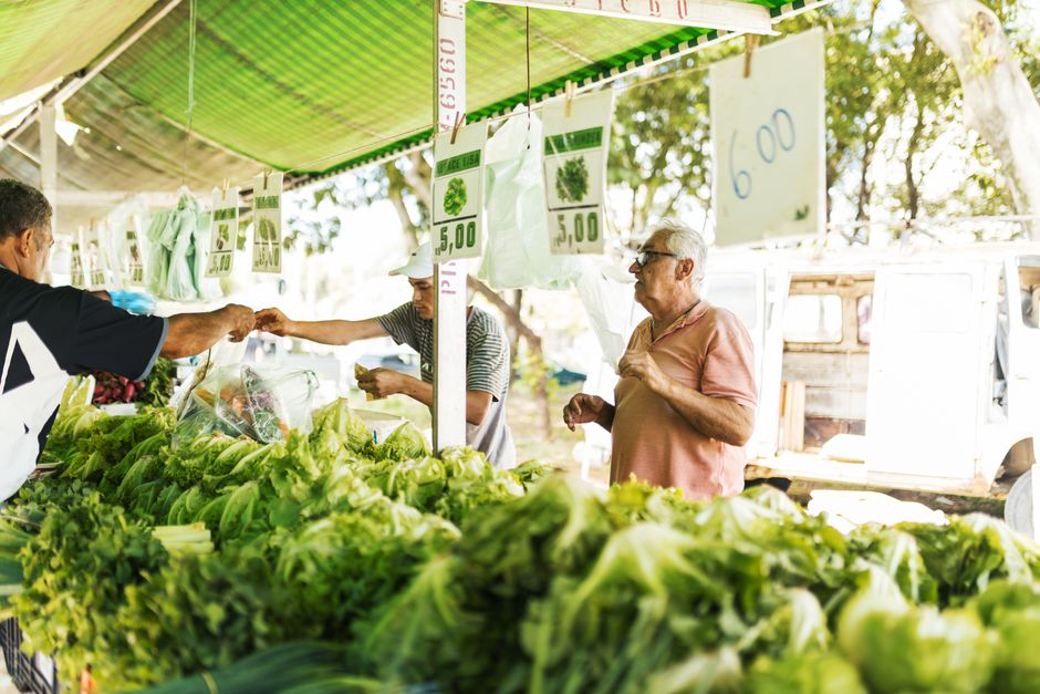 A person selecting fresh, colorful vegetables from a stall at a local farmers market, symbolizing healthy eating choices during a move.