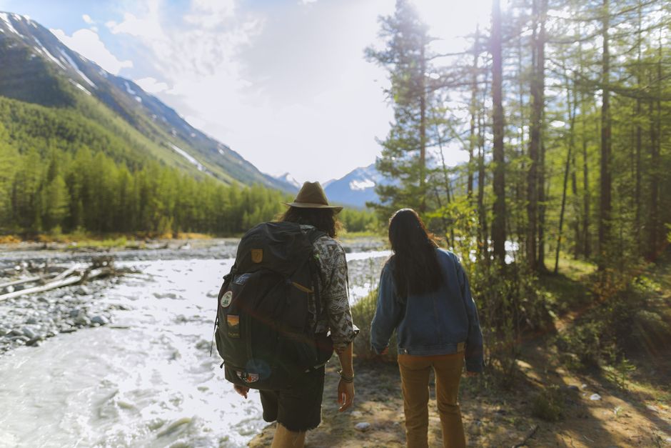 Woman hiking on a sunny trail, pausing to look out over a wide river, embodying a sense of peace and wellness during reloc...