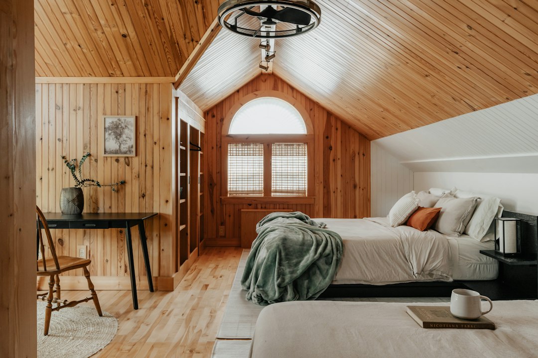 A pair of trail running shoes, a map, and a water bottle resting on a rustic wooden table inside a cozy, sunlit cabin, representing preparation for a runner's getaway.